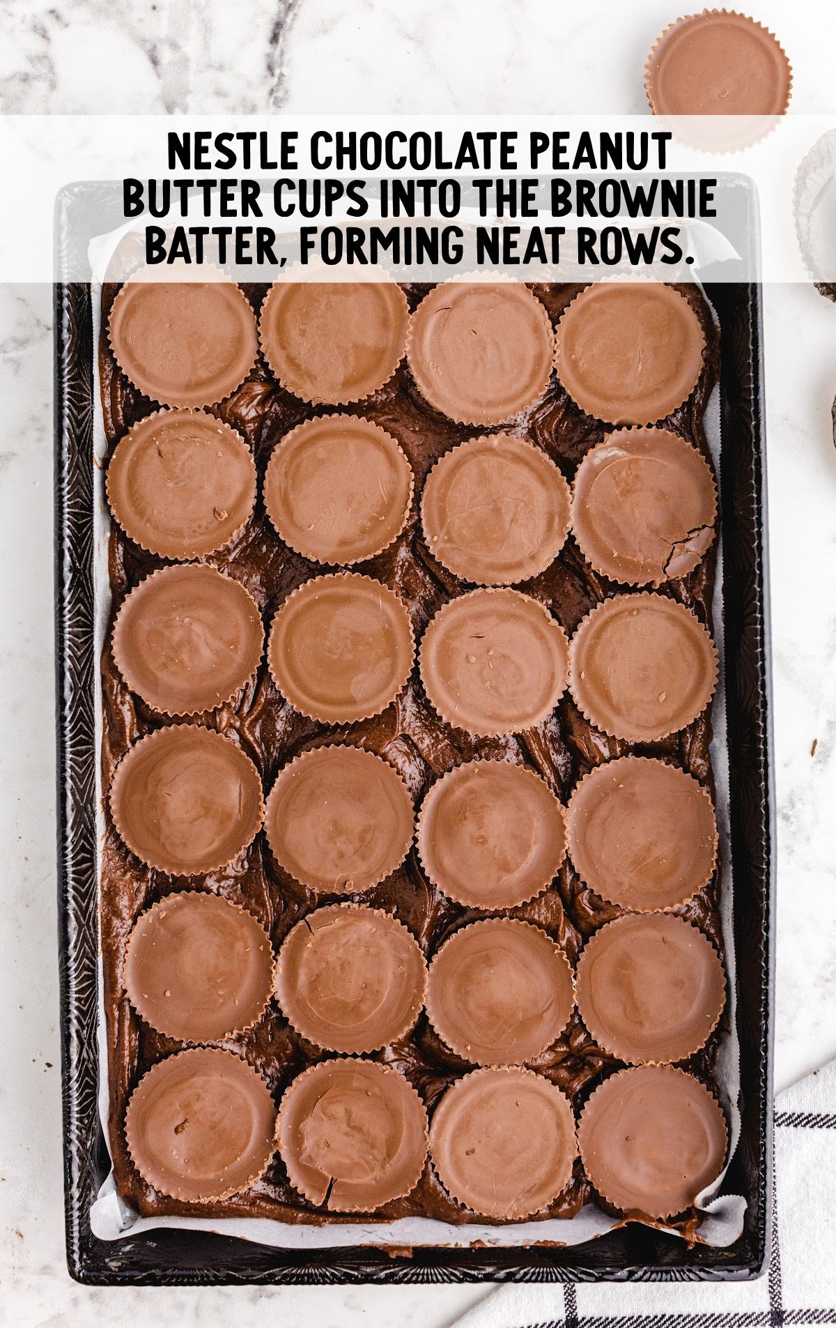 peanut butter cups placed on top of the chocolate batter in the baking pan