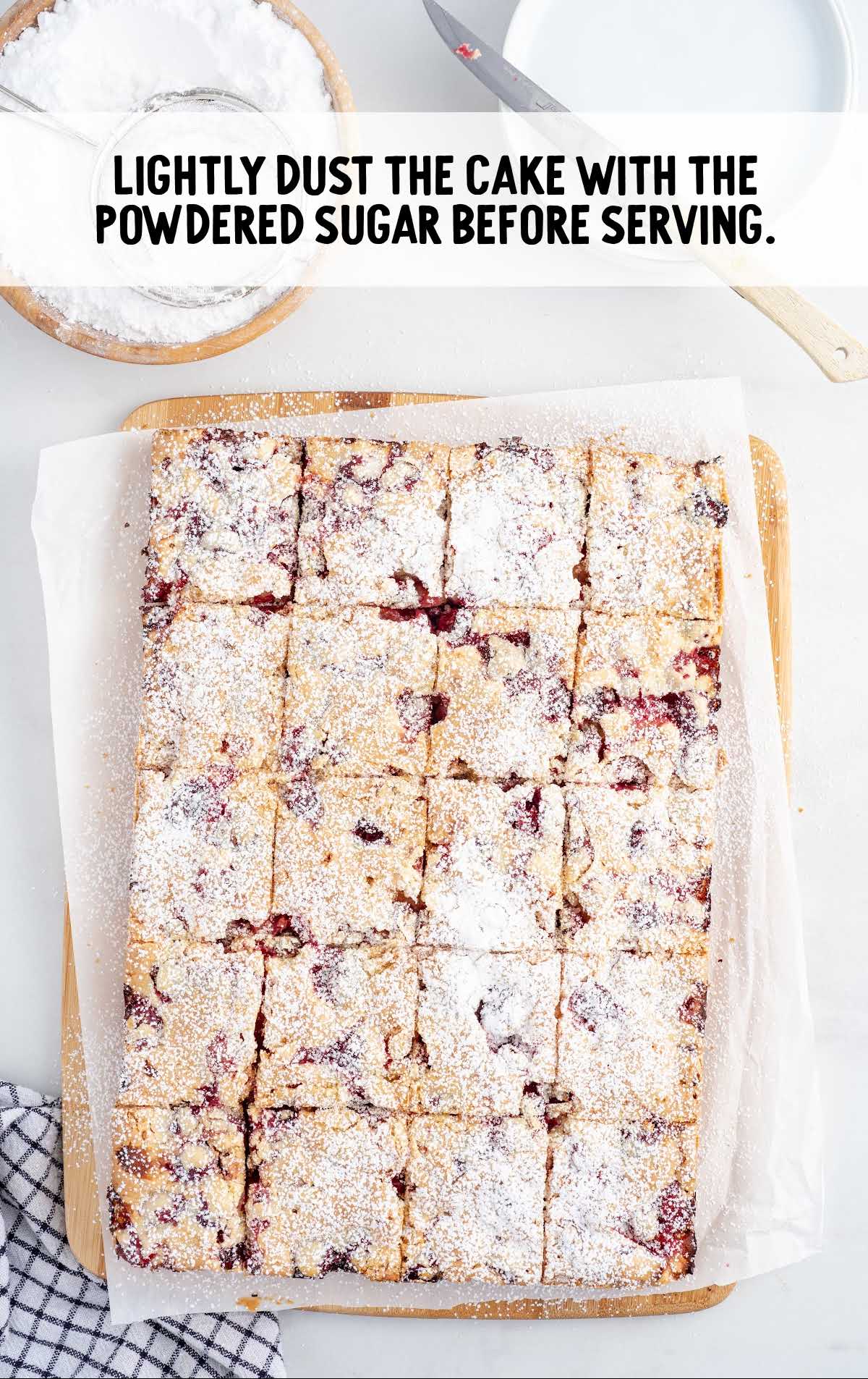 pieces of Cranberry Cake topped with powdered sugar on a parchment lined wooden board