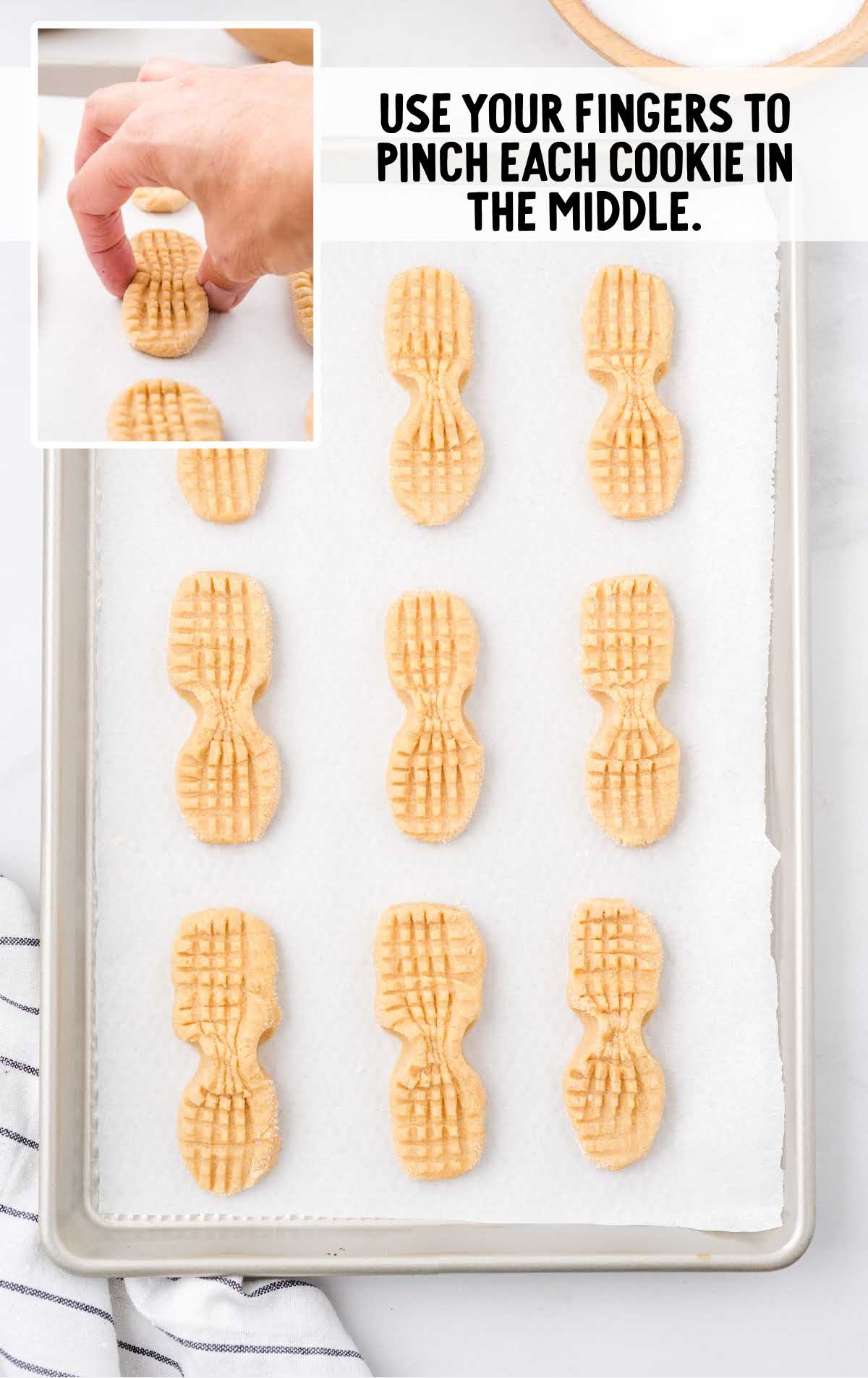 cookies in a baking pan with a hand pressing in the middle to create a indent