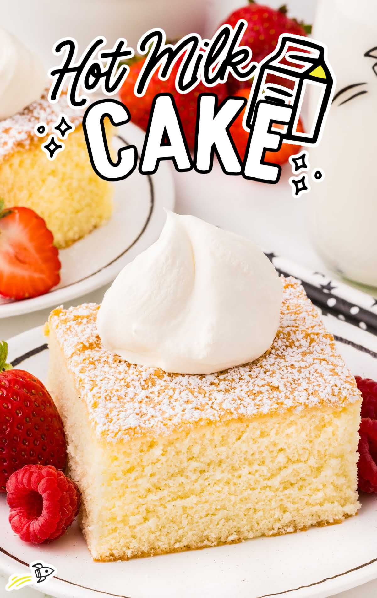 Close-up of a slice of hot milk cake topped with whipped cream, surrounded by fresh strawberries and raspberries on a dessert plate.