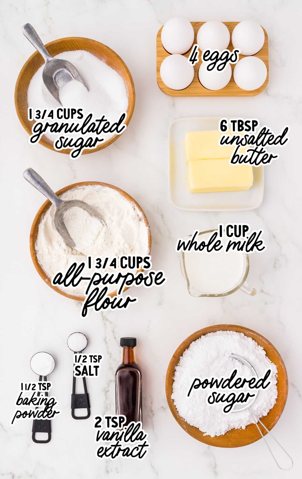 Flat lay of labeled hot milk cake ingredients including flour, sugar, eggs, butter, vanilla, and milk arranged on a white surface.