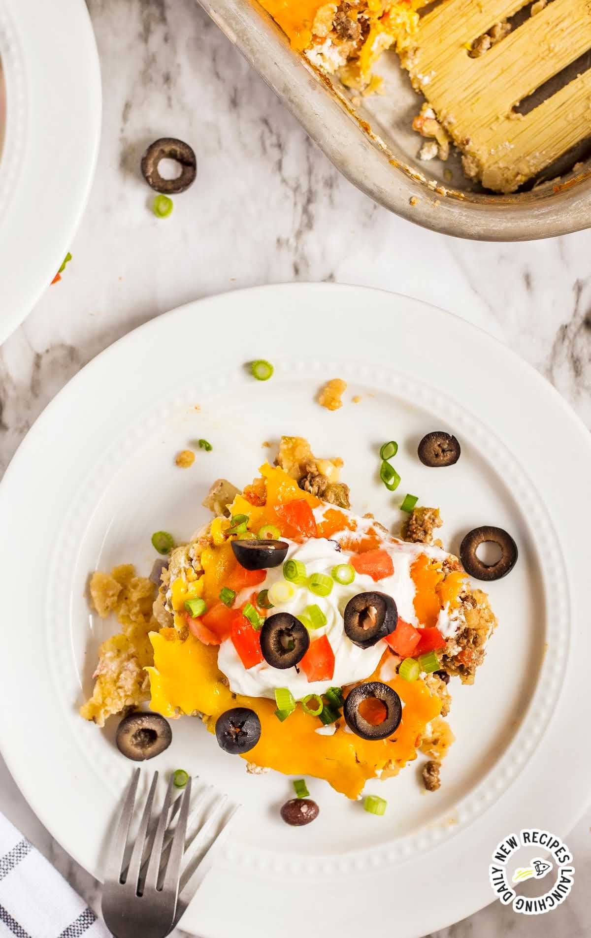 overhead shot of a plate of Mexican Casserole topped with tomatoes and olives