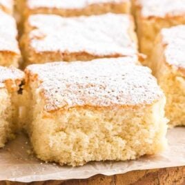 close up shot of milk cakes dusted with powdered sugar on a wooden board