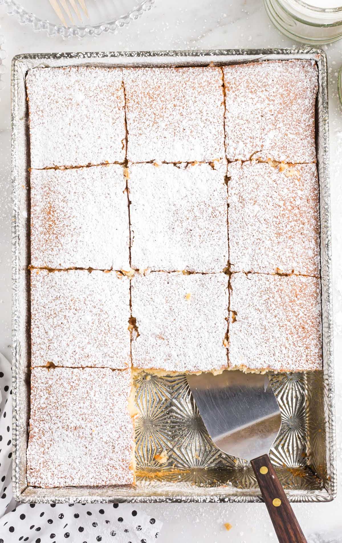 overhead shot of a baking dish of Milk Cakes sprinkled with powdered sugar in a baking dish