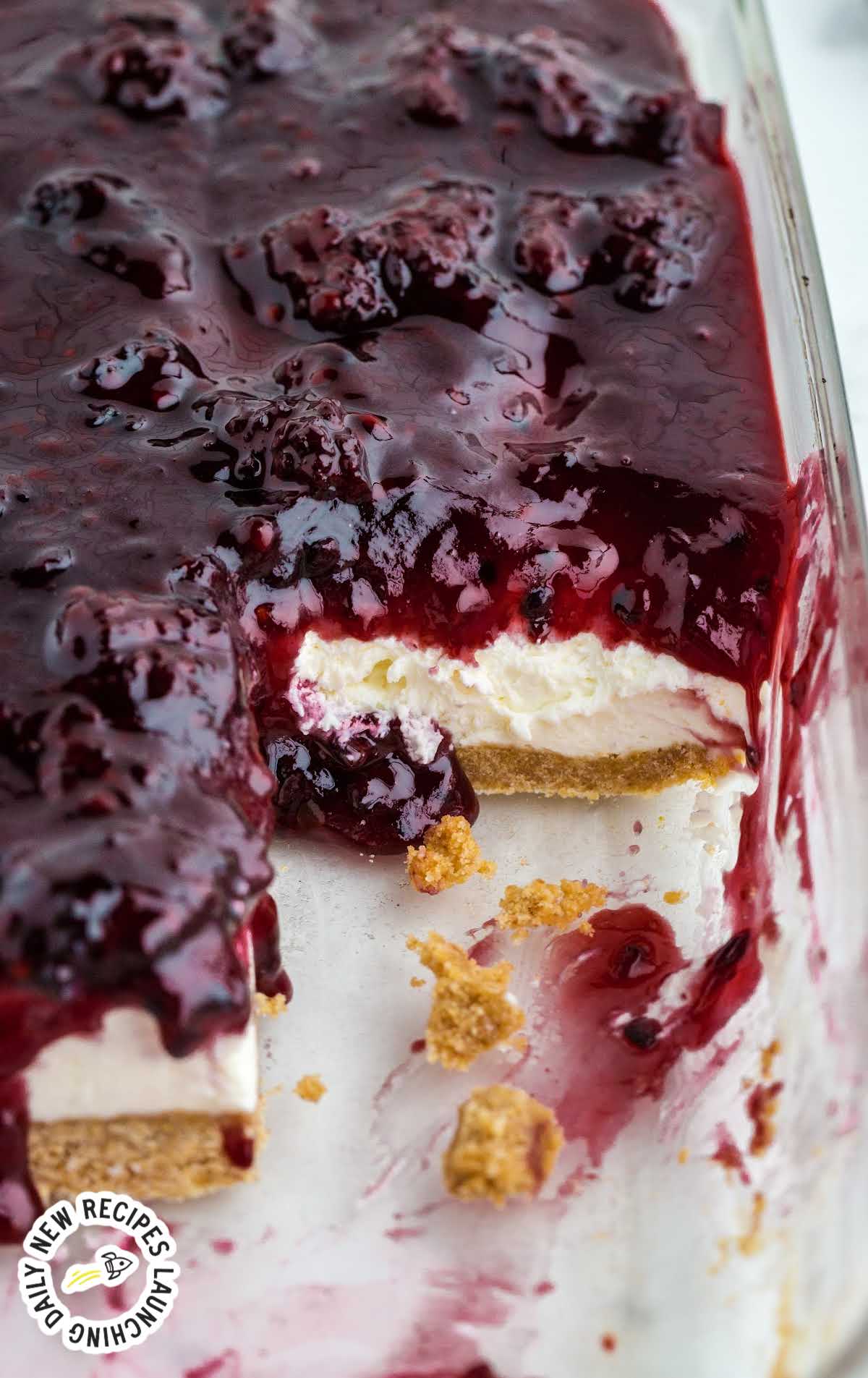 close up shot of blackberry cheesecake in a baking dish with slice missing