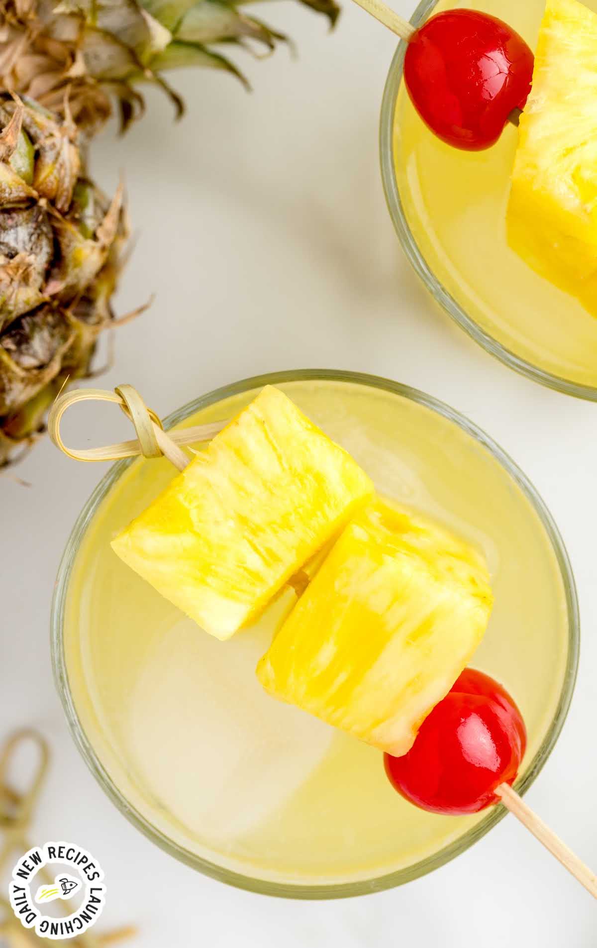 close up overhead shot of a glass of Pineapple Rum Punch garnished with pineapples and a cherry