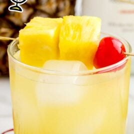 close up shot of a glass of Pineapple Rum Punch garnished with pineapples and a cherry