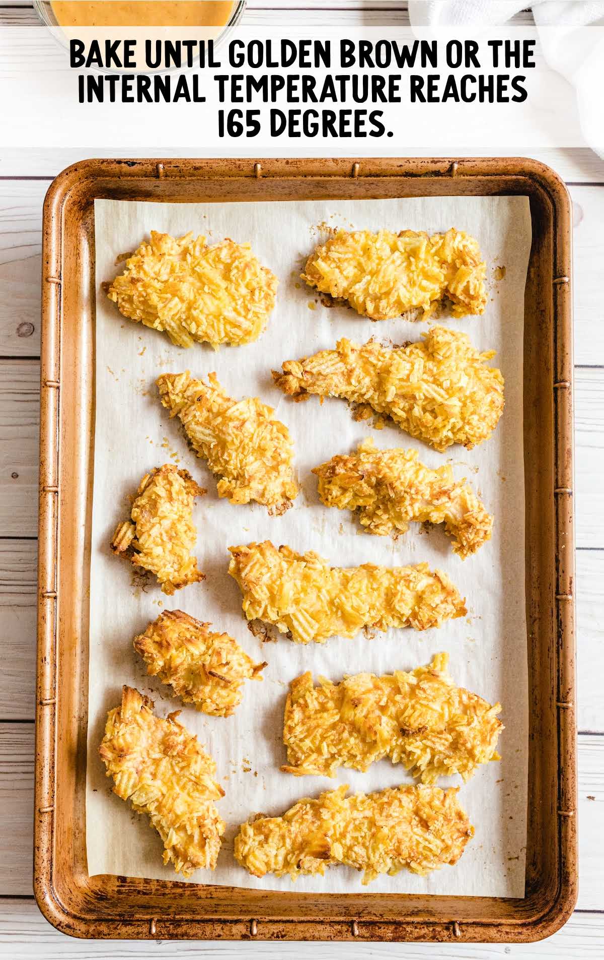 chicken strips baked on a parchment lined baking sheet