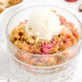close up shot of Rhubarb Crisp topped with a scoop of vanilla ice cream in a bowl