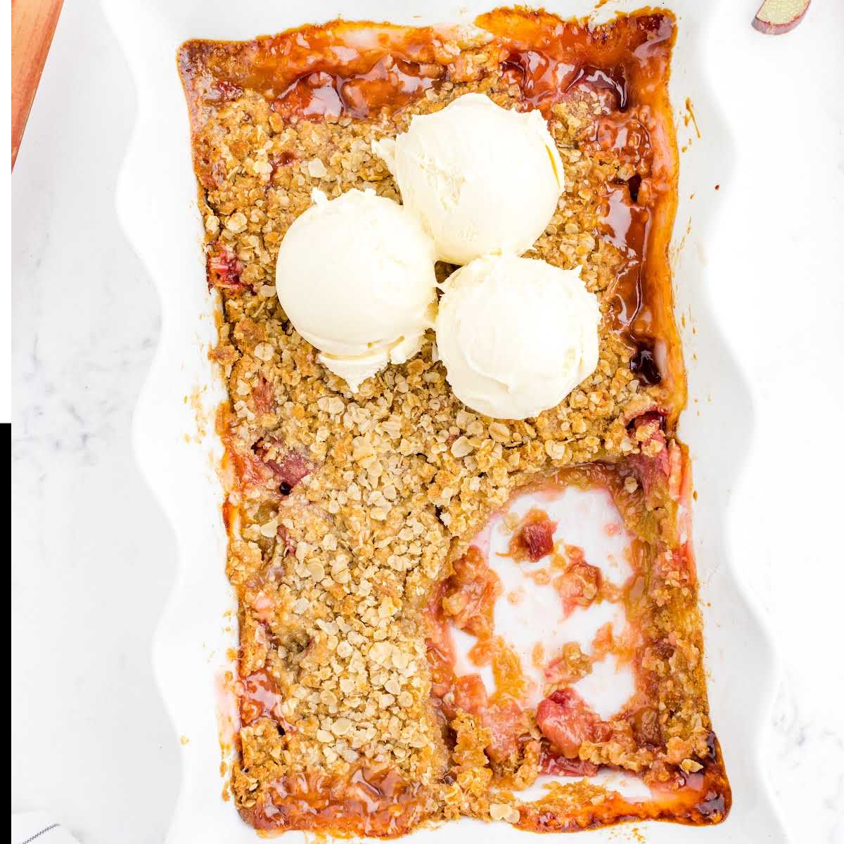 close up overhead shot of Rhubarb Crisp topped with scoops of vanilla ice cream on a plate