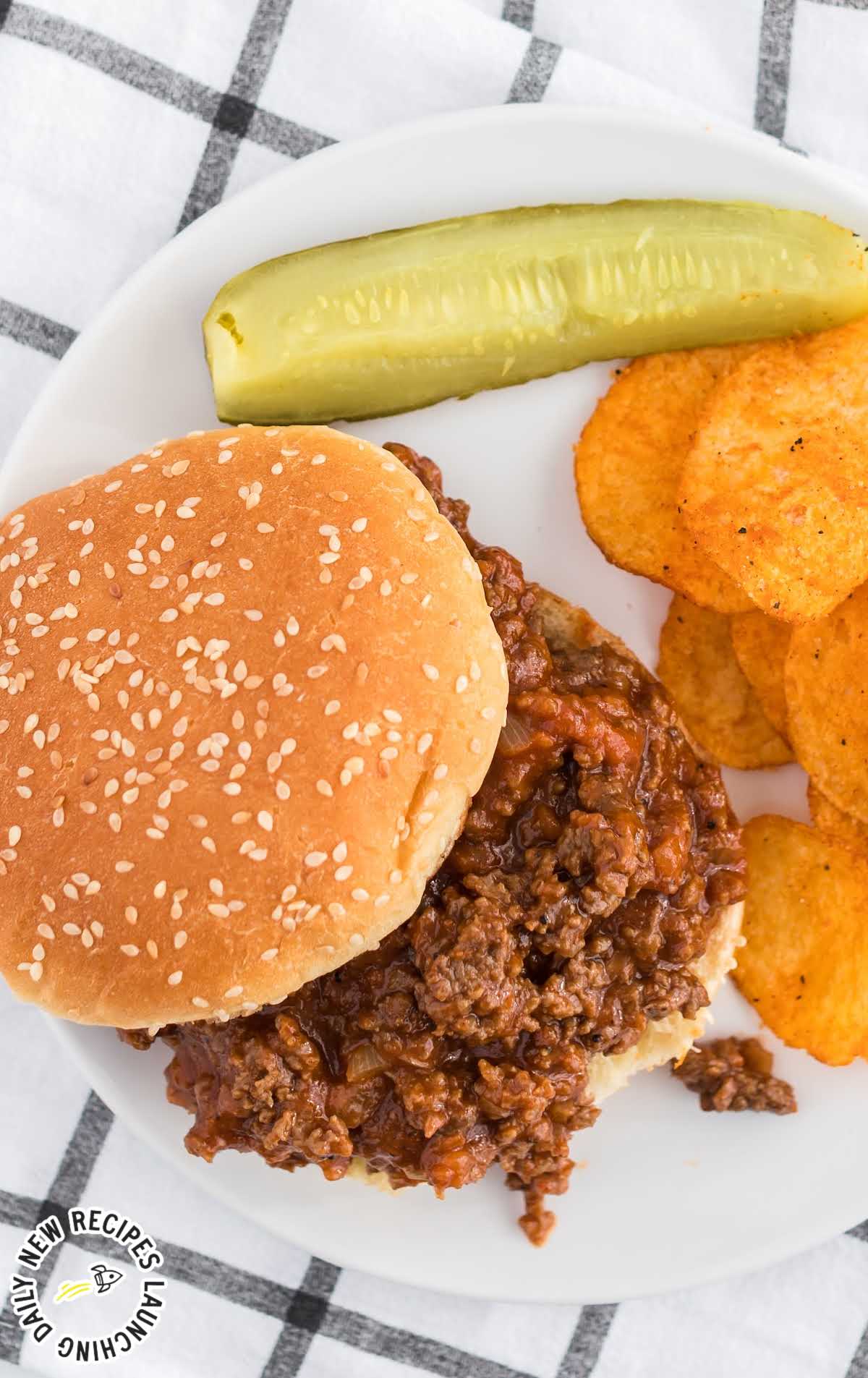 overhead shot of a plate of sloppy Joe sandwich with a pickle and chips
