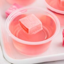 a close up shot of a Starburst Jello Shot in a cup topped with a pink starburst