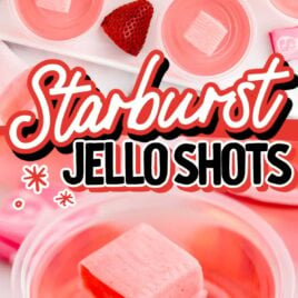 a close up shot of a Starburst Jello Shot in a cup topped with a pink starburst with a jello shot tray and strawberries