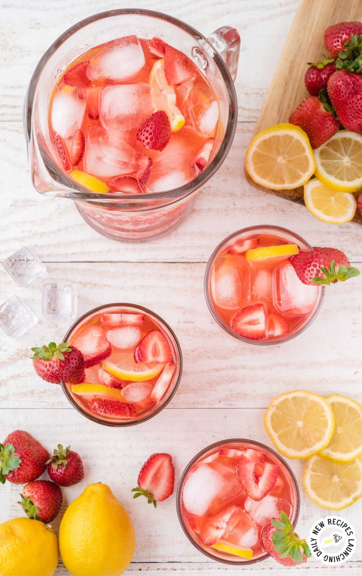 overhead shot of glasses and a pitcher full of Strawberry Lemonade garnished with strawberries and lemon