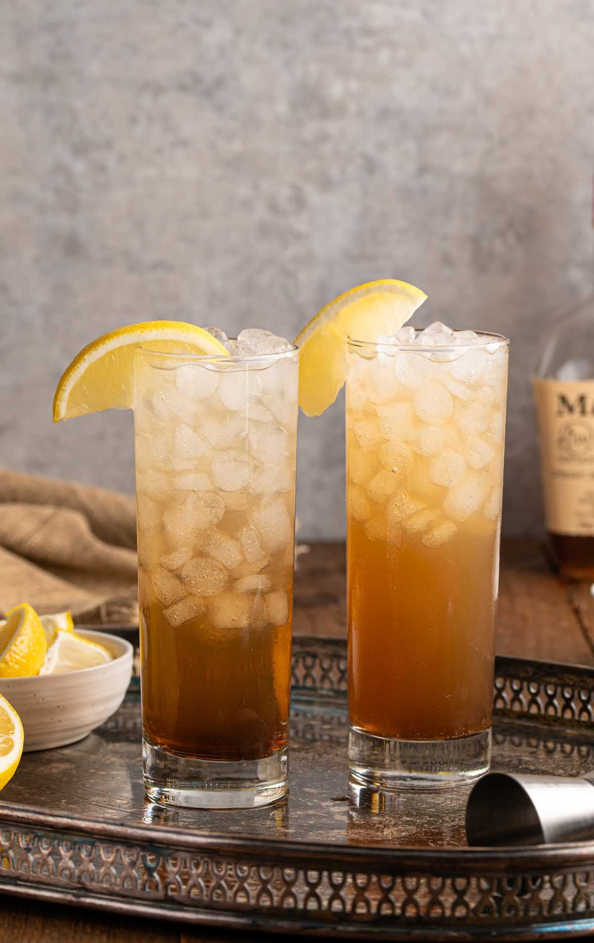 Two tall glasses of Texas Tea with ice and lemon wedges on a decorative silver tray.