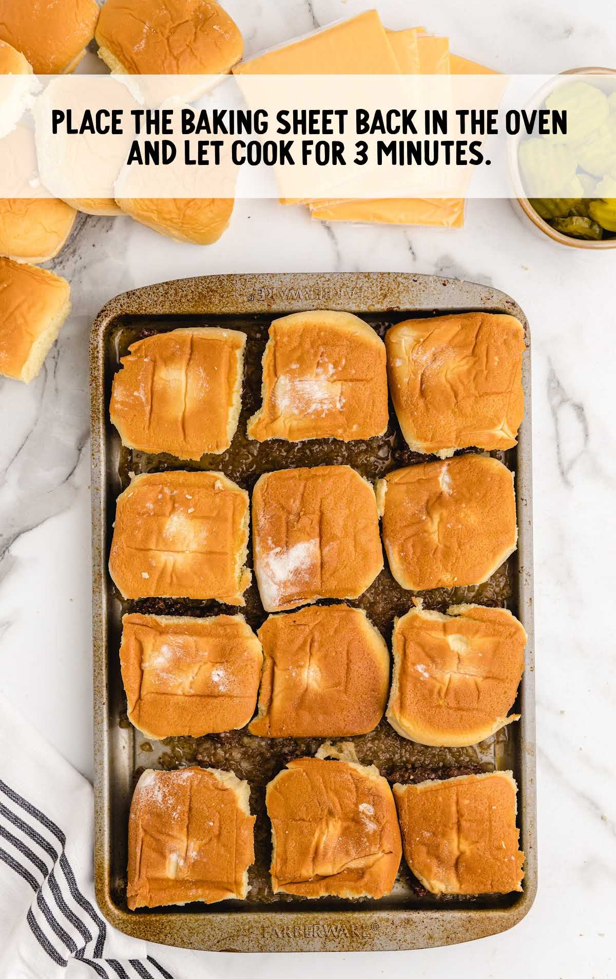 ground beef mixture topped with buns after being baked in a baking sheet