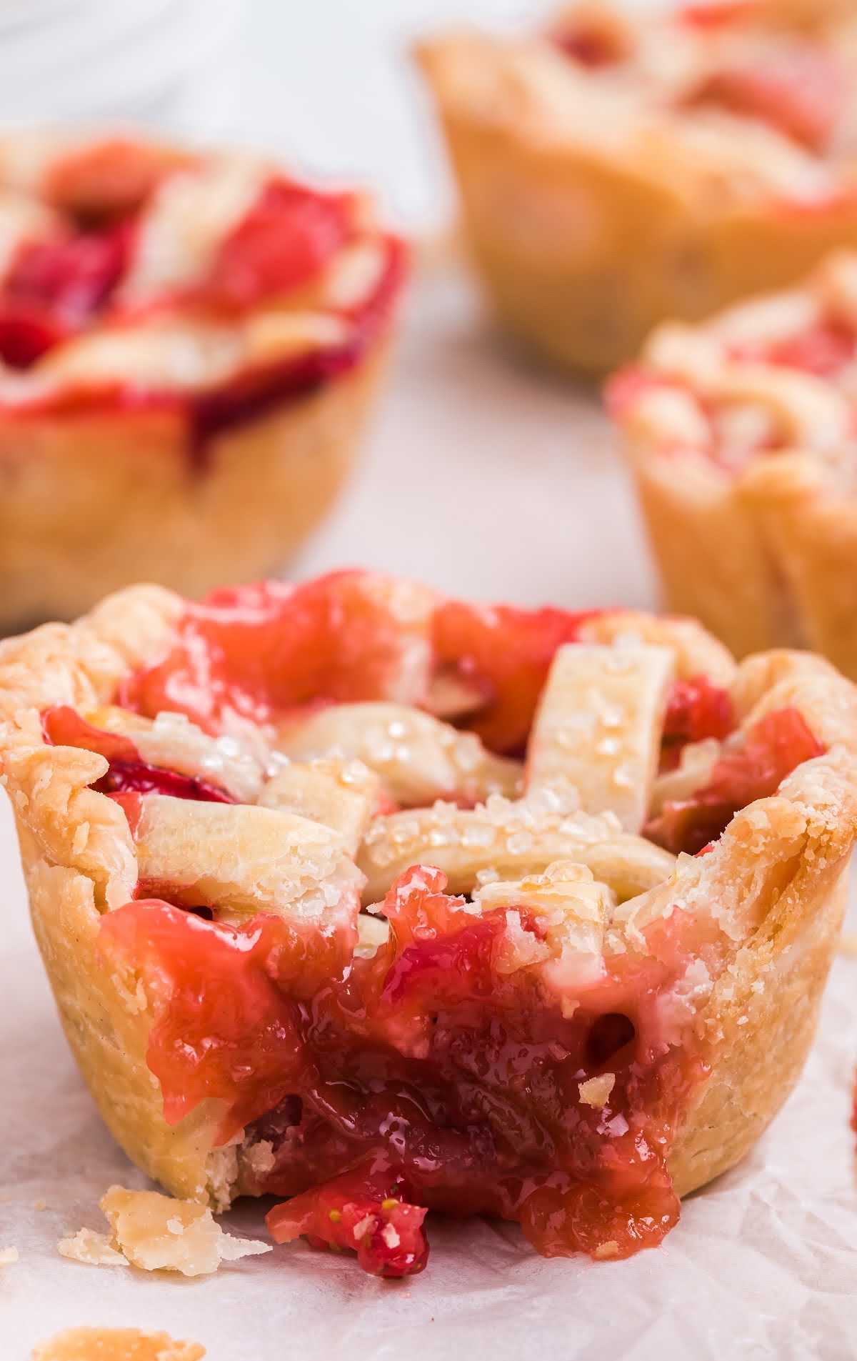 close up shot of a Mini Rhubarb and Strawberry Pies on a parchment paper