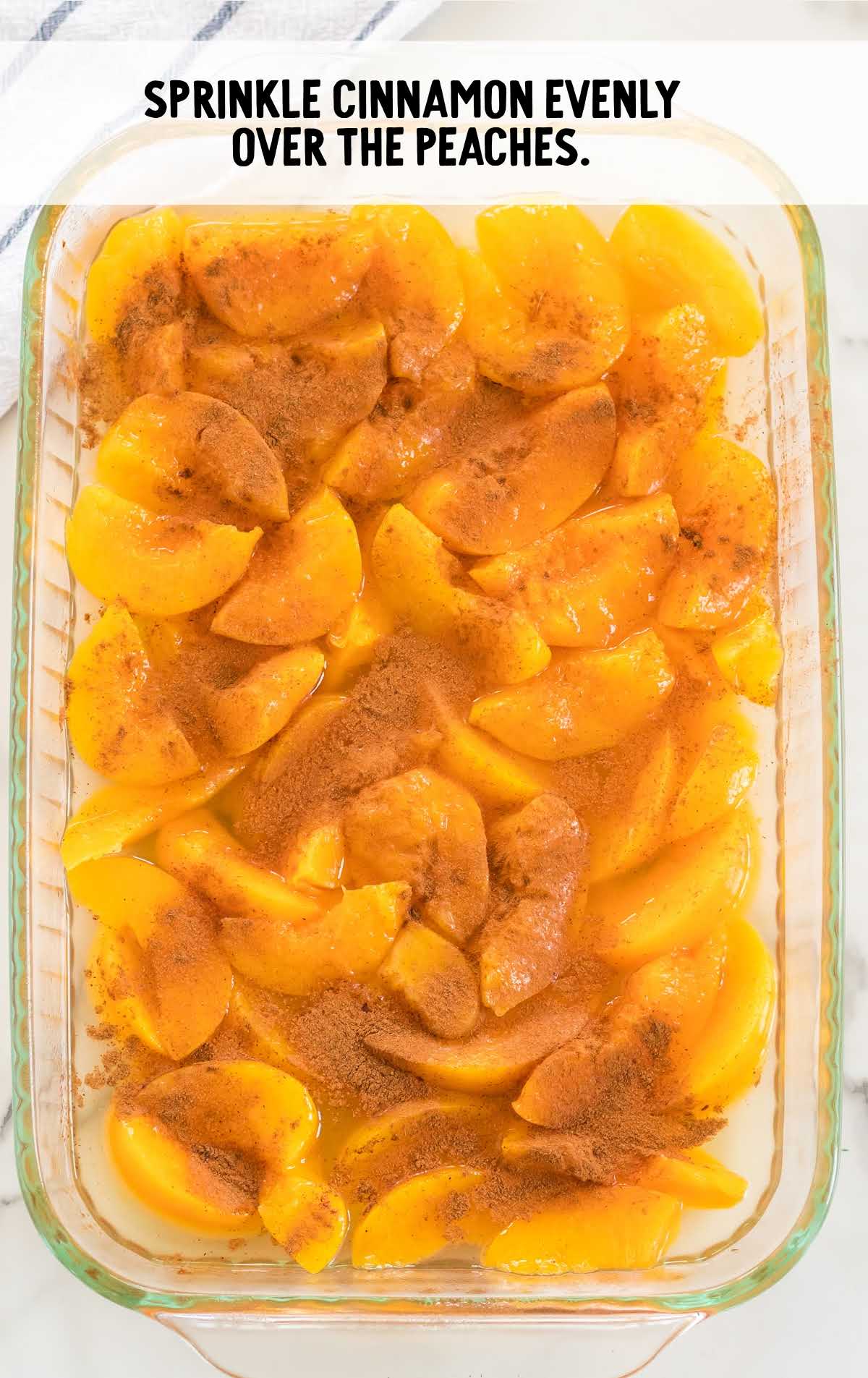 cinnamon sprinkled on top of the peaches in the baking dish