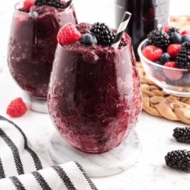 close up shot of red wine slushies topped with mixed berries on a glass cup