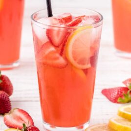 close up shot of a glass full of Strawberry Lemonade garnished with strawberries and lemon