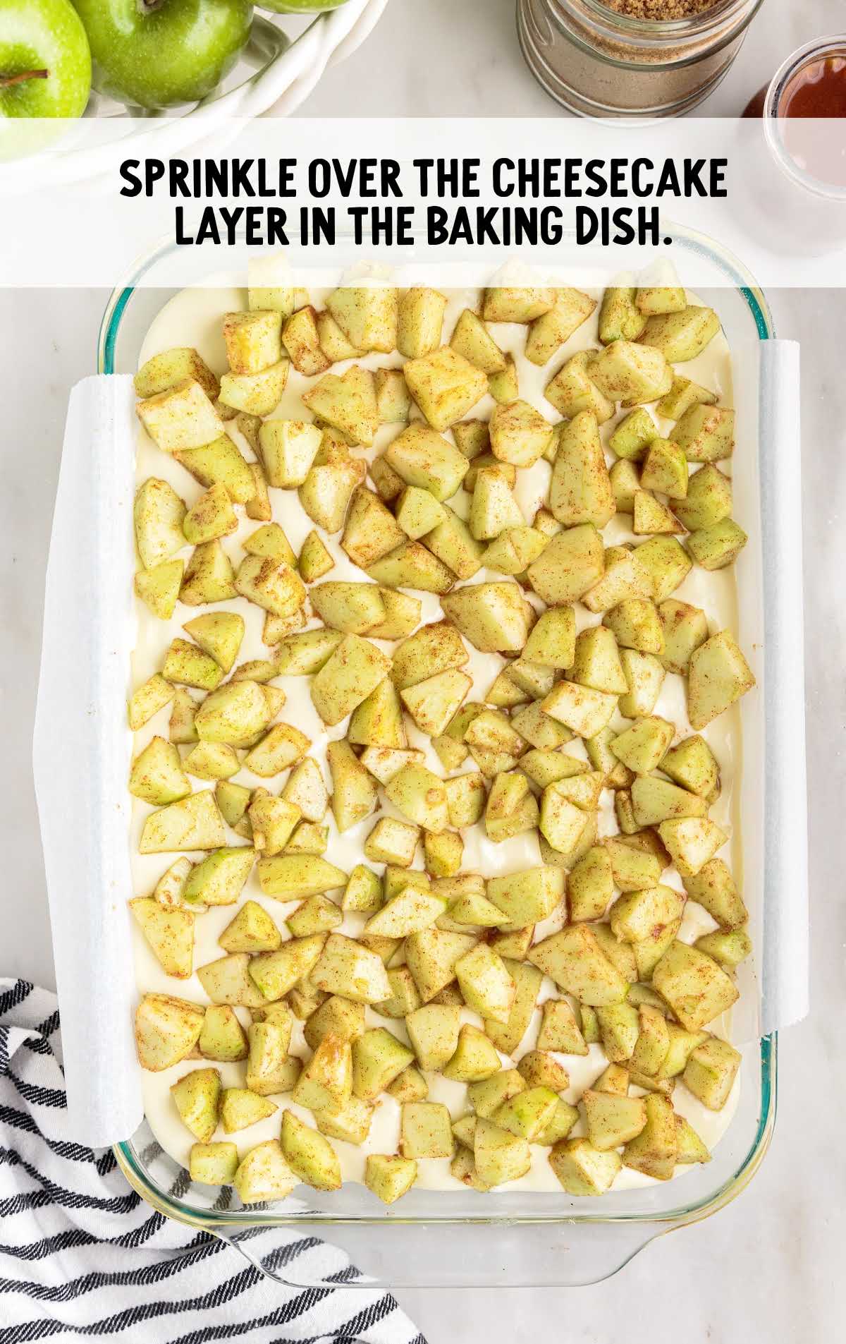 cinnamon apples sprinkled over the cheesecake layer in the baking dish