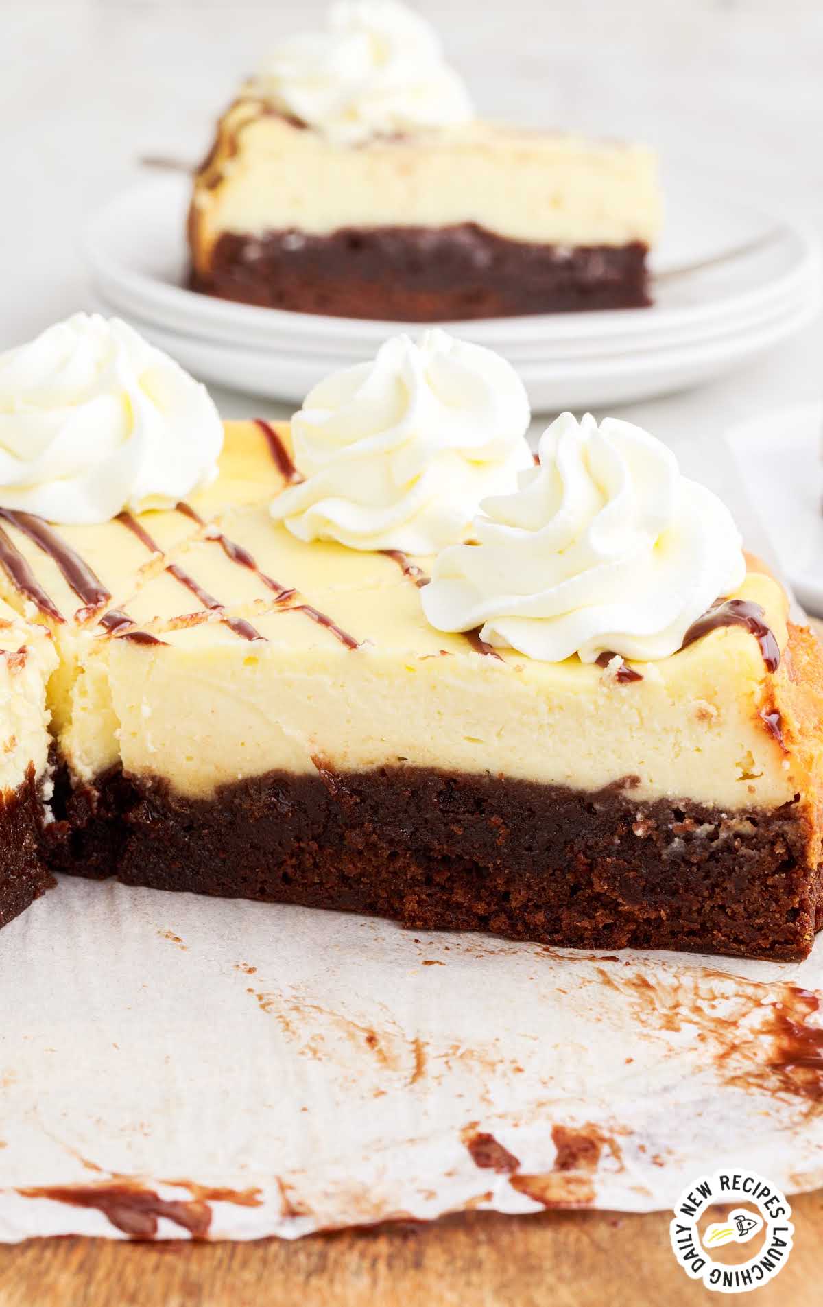 a Brownie Bottom Cheesecake drizzled with chocolate sauce and topped with whipped cream