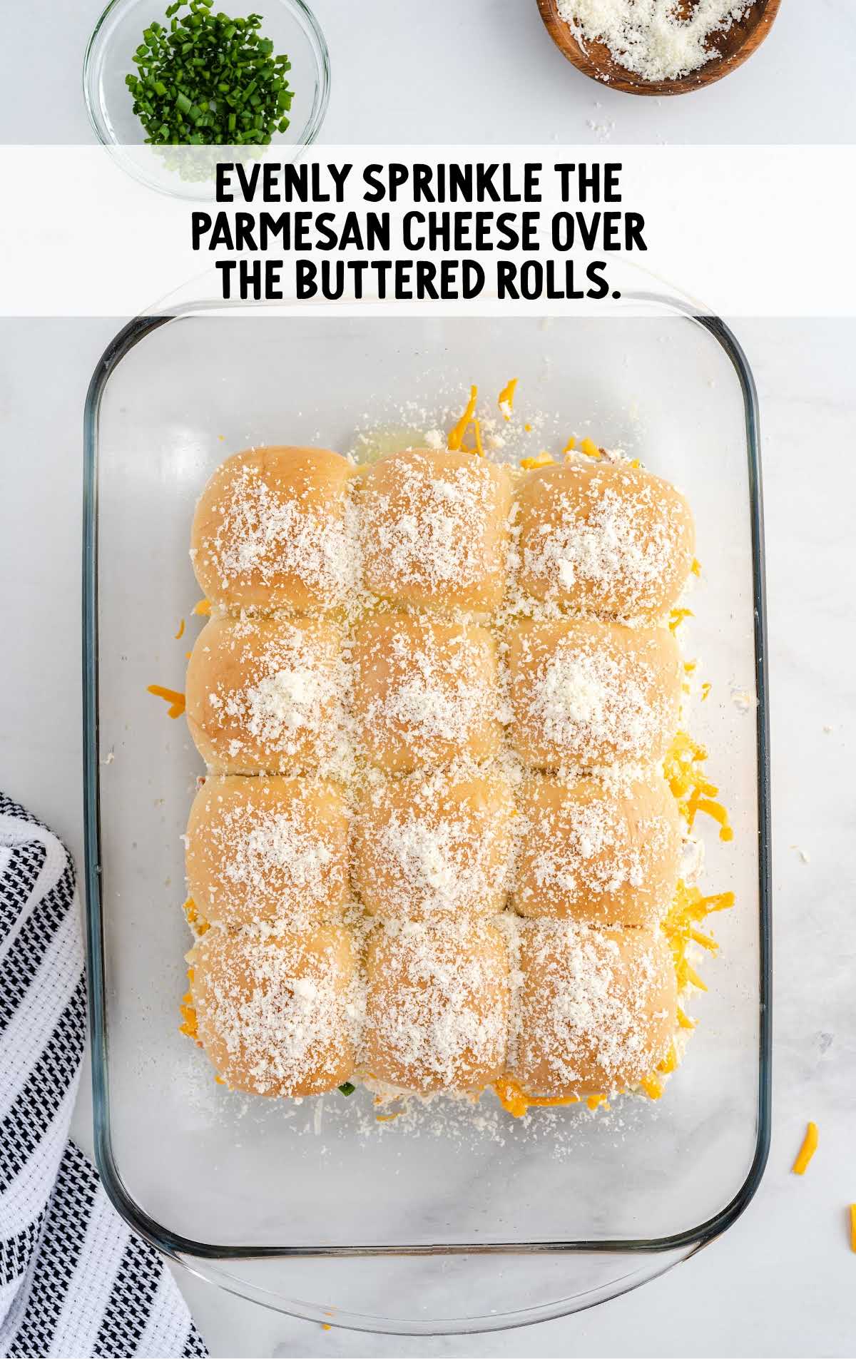 parmesan cheese sprinkled over the buttered rolls in a baking dish