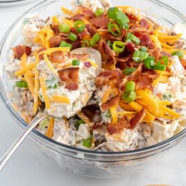 close up shot of Loaded Baked Potato Salad with a spoon grabbing a piece