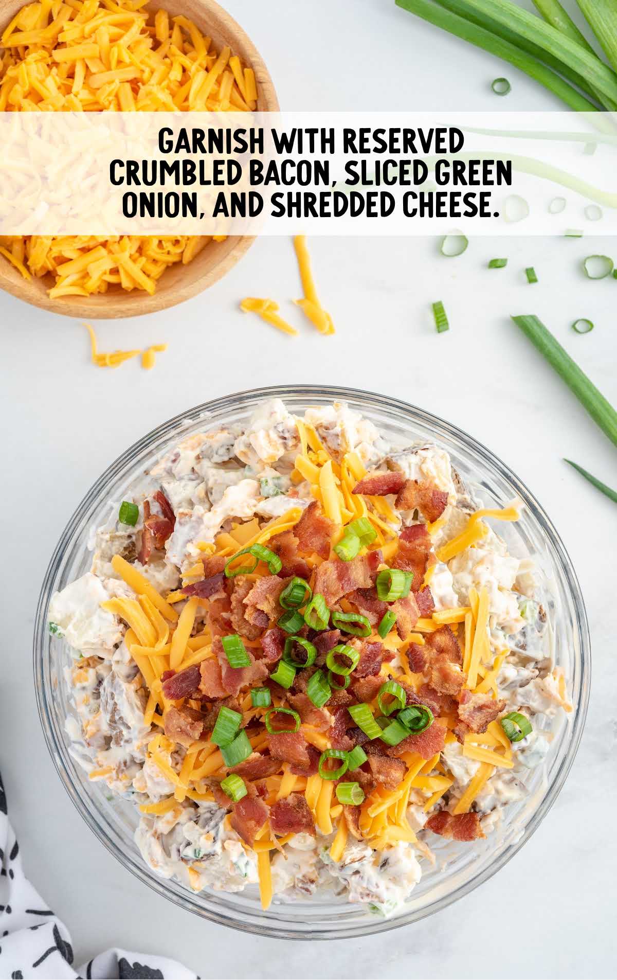 bacon, sliced green onion, and shredded cheese topped on top of the salad in a bowl