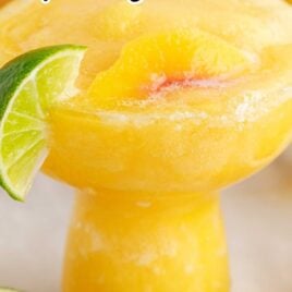 close up shot of Peach Margaritas in a glass topped with a slice of lime and peach