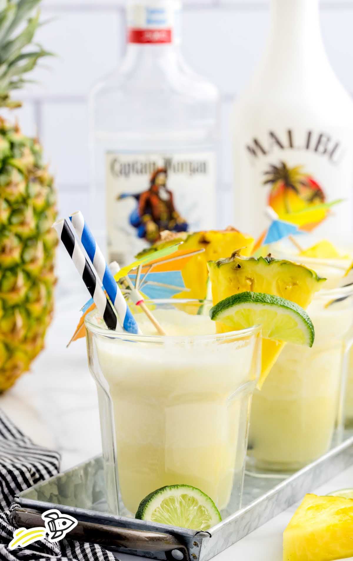 close up shot of Pineapple Coolers in a drink tray topped with limes and pineapples slices