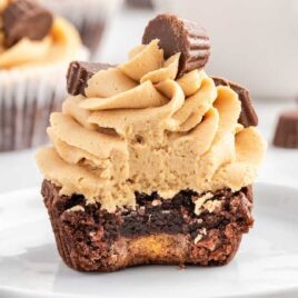 a close up shot of Reese's Peanut Butter Cupcake with a bite taken out of it on a plate