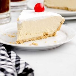 a slice of Root Beer Float Pie topped with a cherry on a plate
