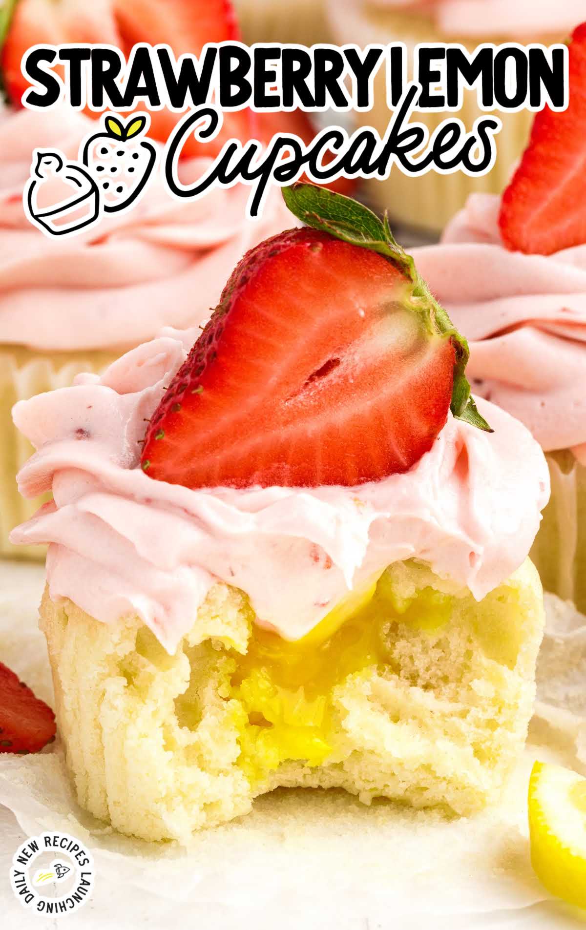 a close up shot of Strawberry Lemon Cupcake topped with a strawberry with a bite taken out of it