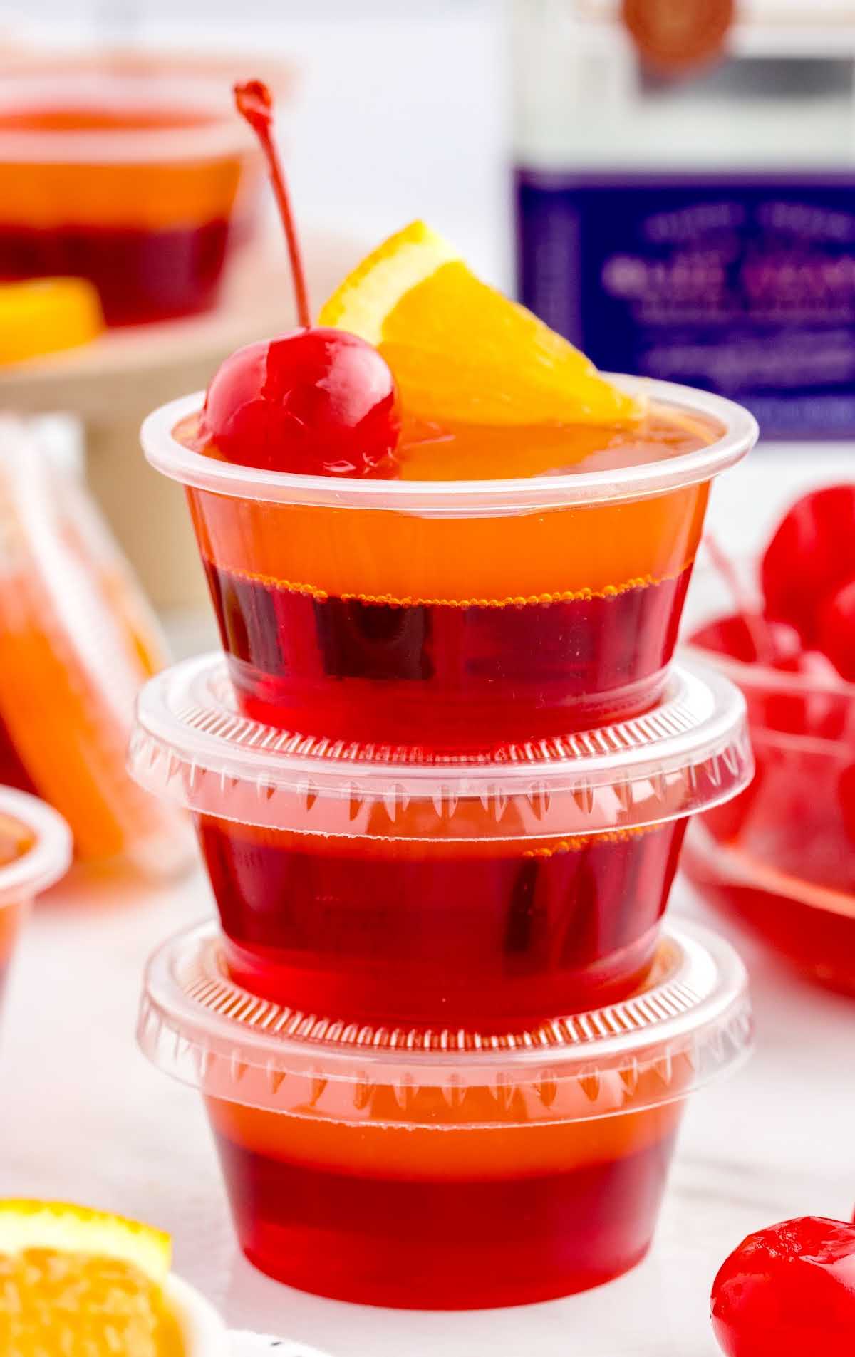 close up shot of containers of Tequila Sunrise Jello Shots stacked on top of each other