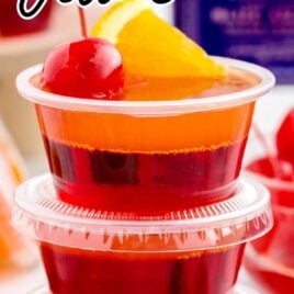 close up shot of containers of Tequila Sunrise Jello Shots stacked on top of each other topped with an orange slice and cherry