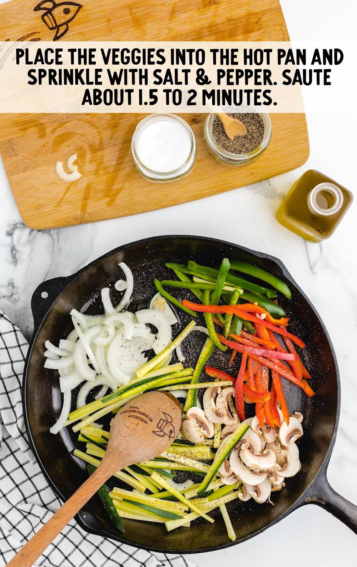 veggies placed in a pan with slat and pepper with a wooden spoon