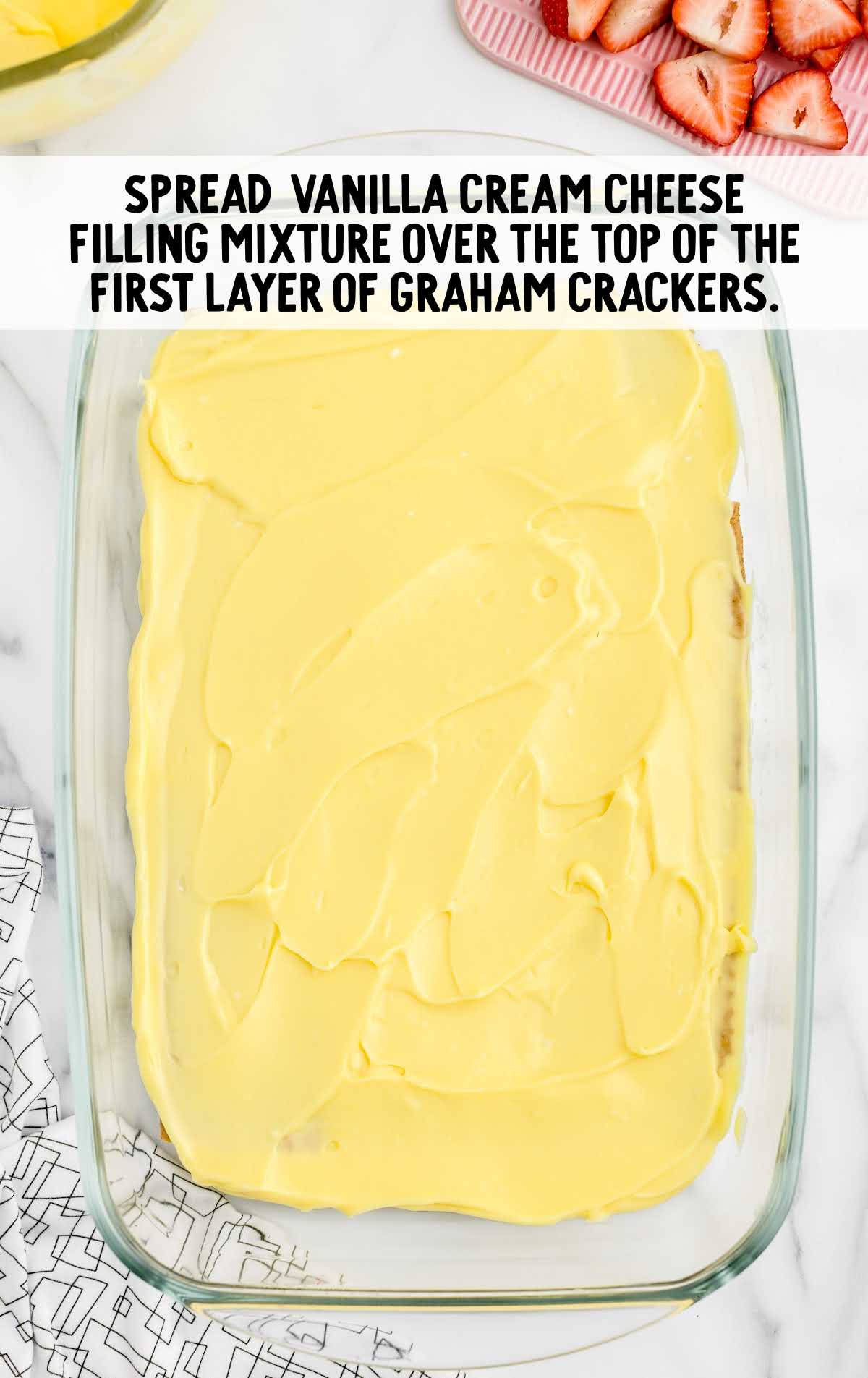 vanilla cream cheese filling mixture spread over the first graham cracker in a baking dish