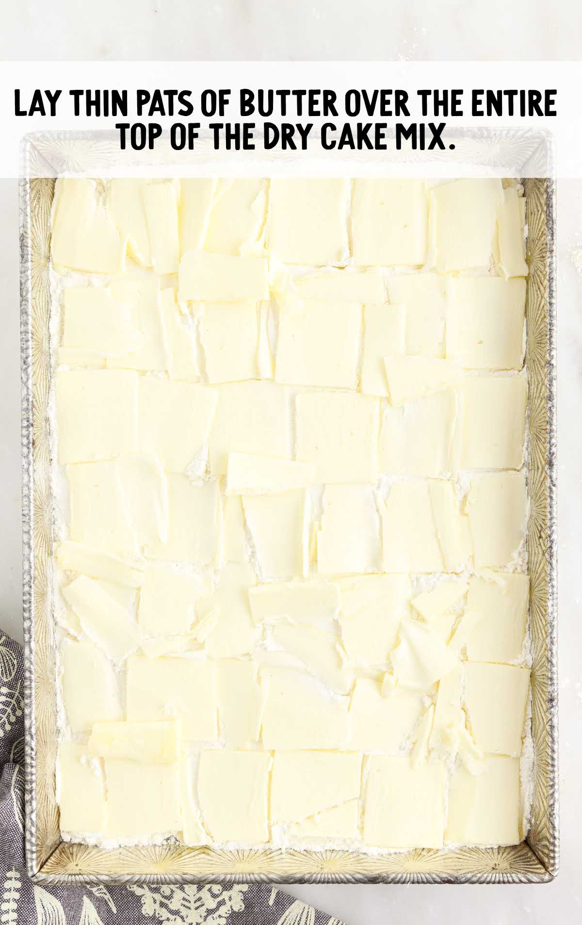thin pats of butter laid on top of the cake in in a baking dish