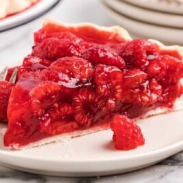 a close up shot of a slice of raspberry pie on a plate with a fork