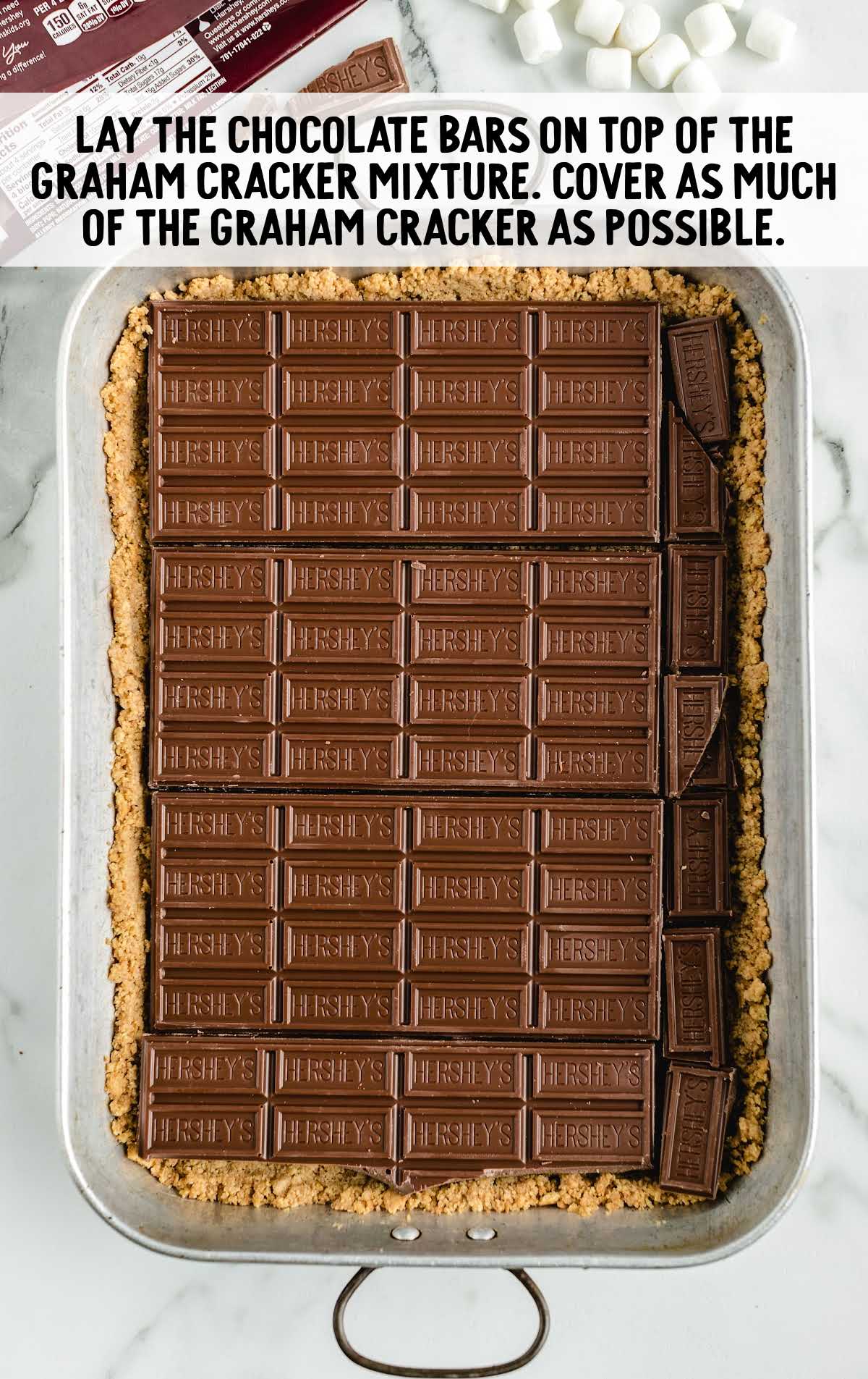 chocolate bars placed on top of graham cracker mixture in a baking dish