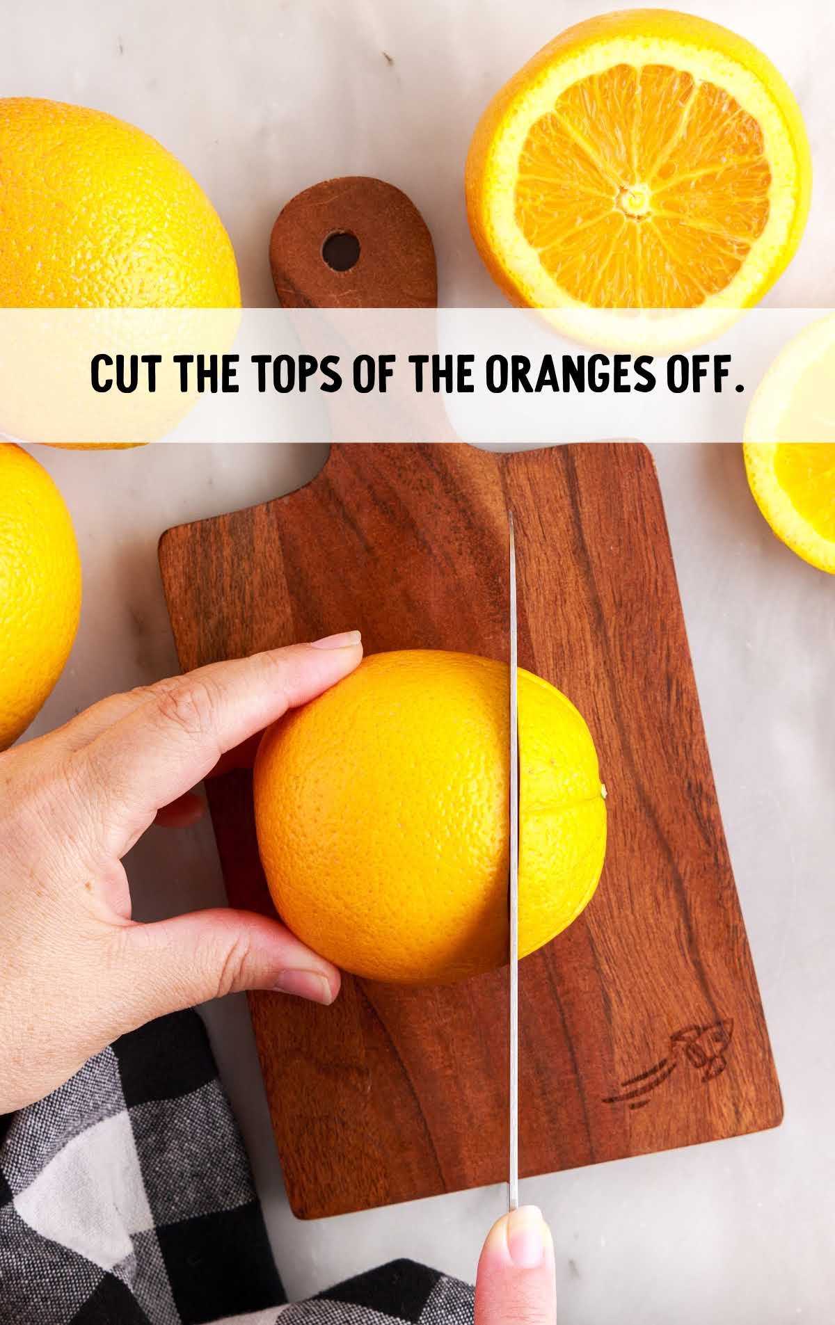 orange getting top cut off on a wooden cutting board