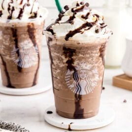 a close up shot of a Frappuccino topped with whipped cream, chocolate syrup, and chocolate chips