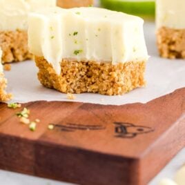 close up shot of a slice of Key Lime Fudge on a wooden cutting board with a slice taken out