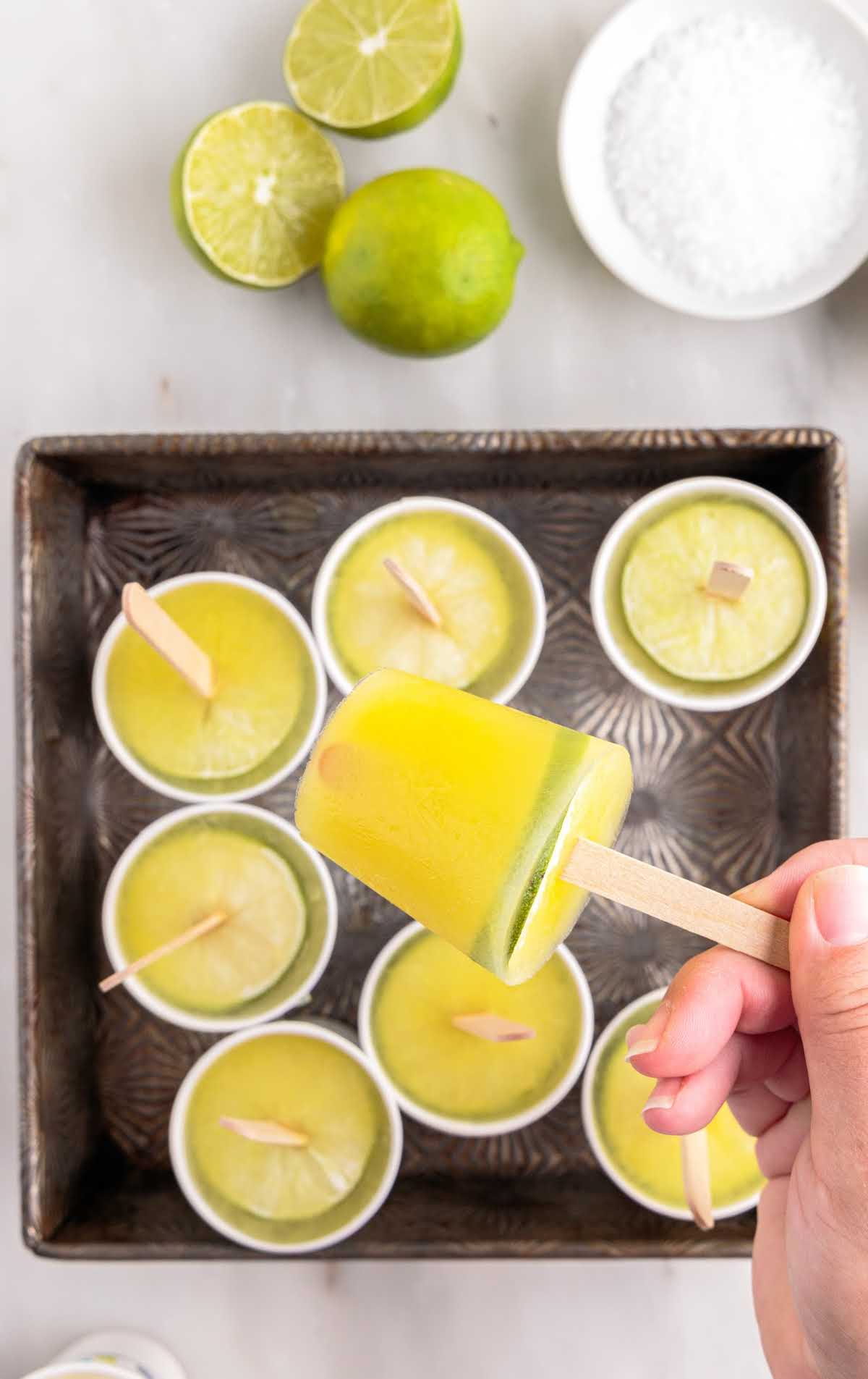 close up shot of Margarita Popsicles with slices of lime in a baking dish