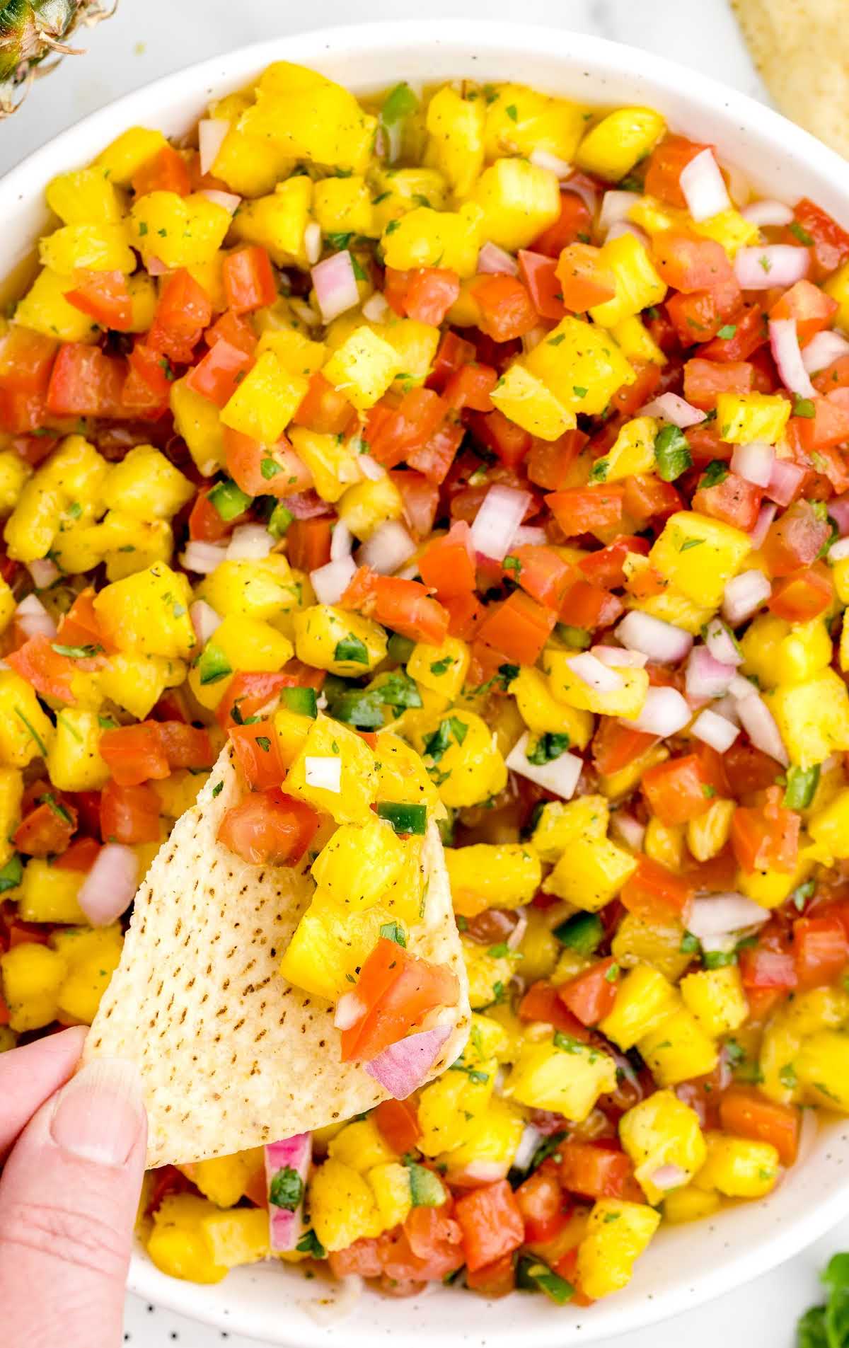 overhead shot of Pineapple Salsa in a bowl with a chip