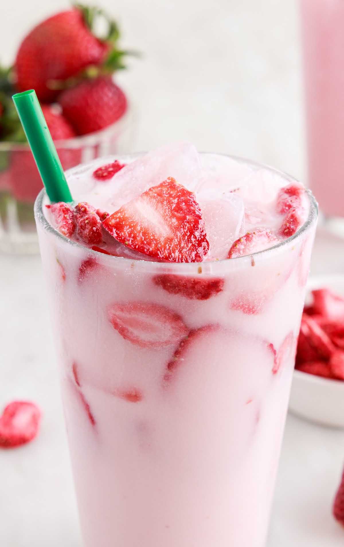 close up shot of a cup of Pink Drink topped with slices of strawberries