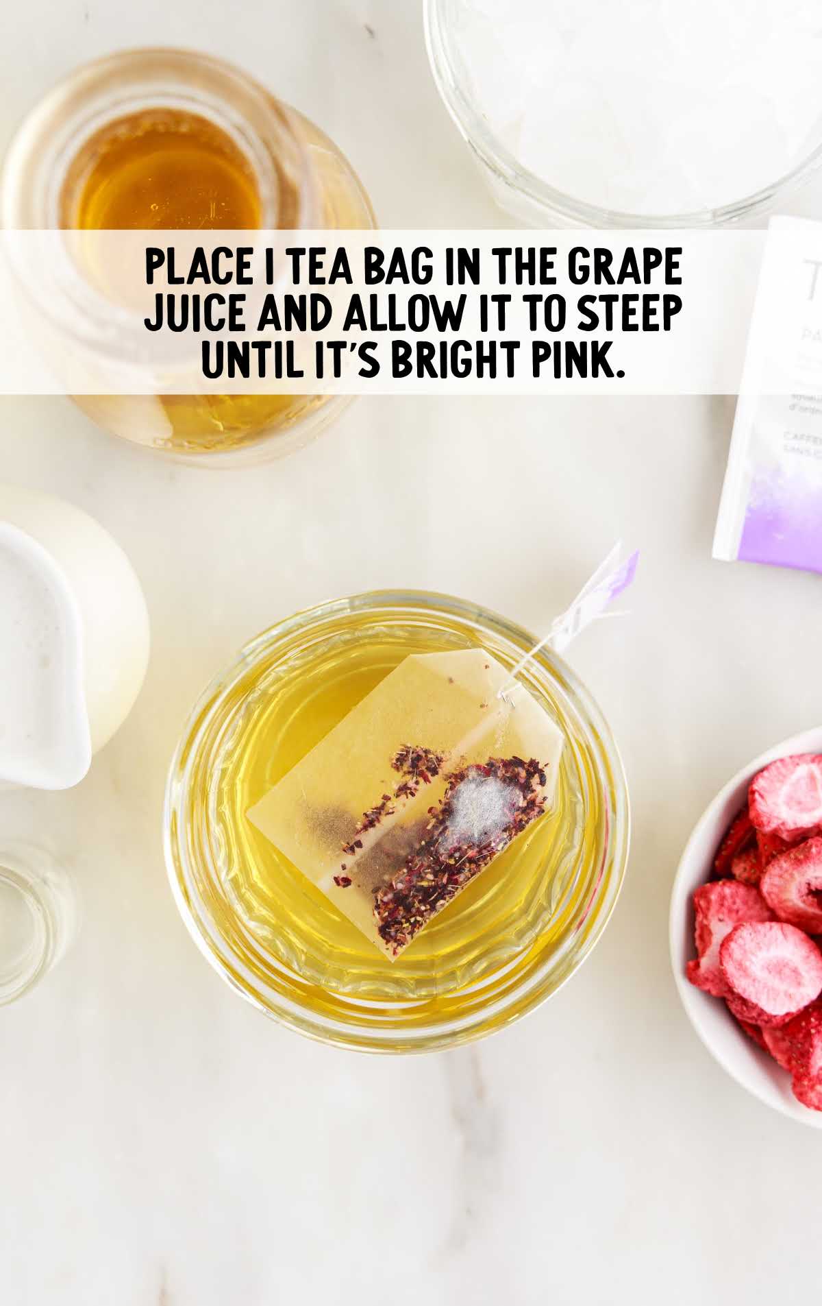 tea bag placed in grape juice in a glass