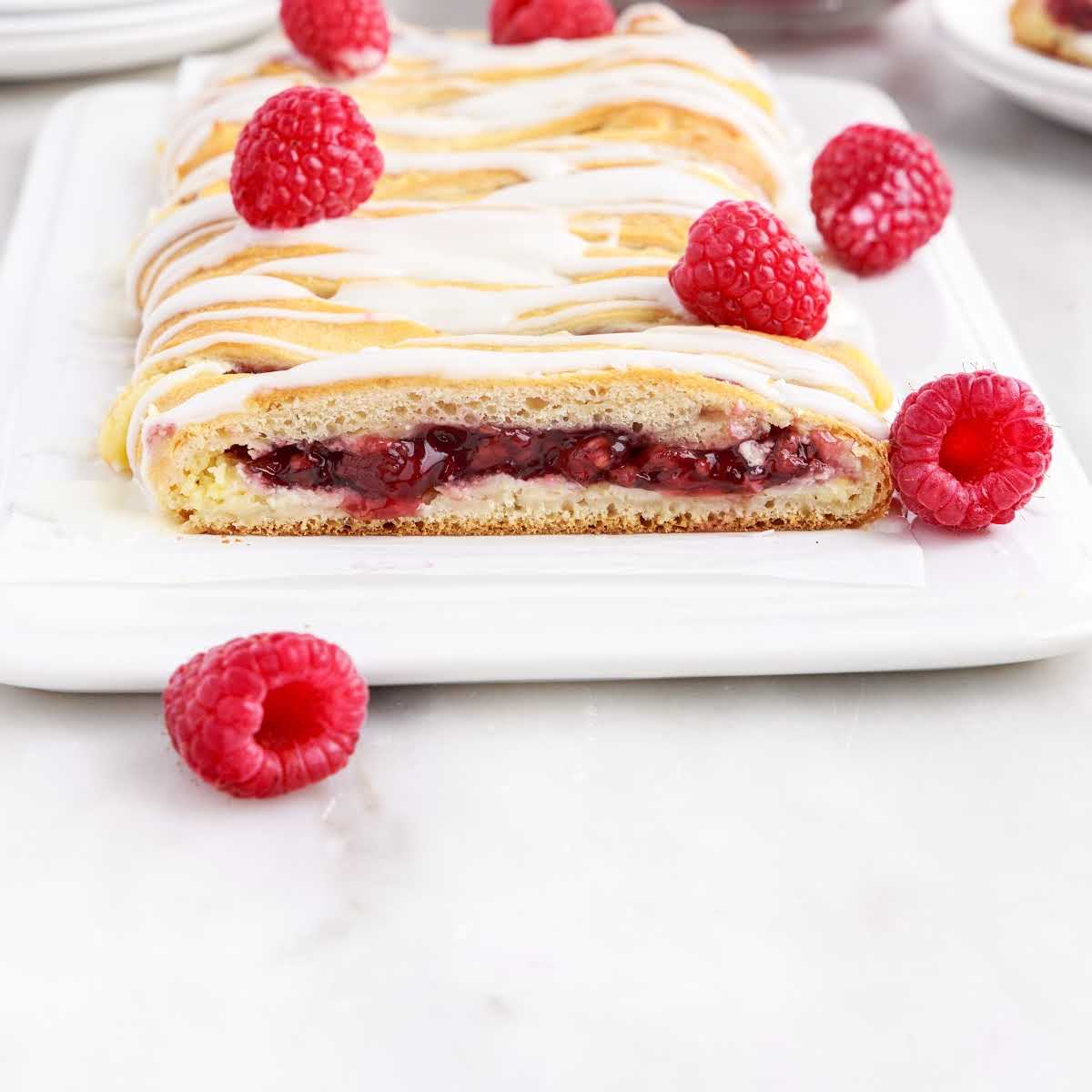 close up shot of raspberry breakfast braid on a plate with raspberries on the side