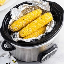 close up shot of Slow Cooker Corn on the Cob on foil and a crockpot